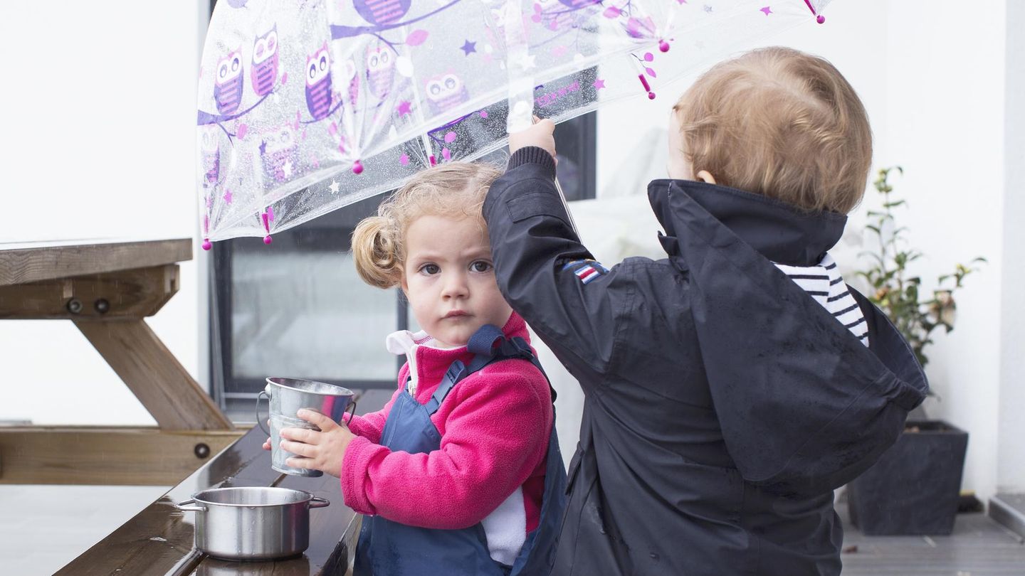 Zwei kleine Kinder spielen im Regen