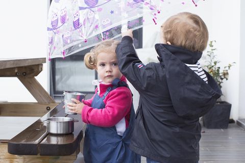 Zwei kleine Kinder spielen im Regen