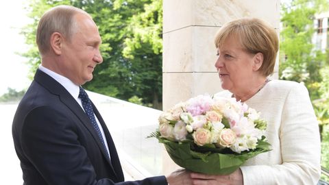 Wladimir Putin begrüßt Angela Merkel mit einem Blumenstrauß