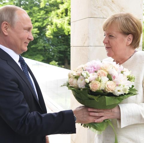 Wladimir Putin begrüßt Angela Merkel mit einem Blumenstrauß