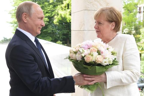 Wladimir Putin begrüßt Angela Merkel mit einem Blumenstrauß