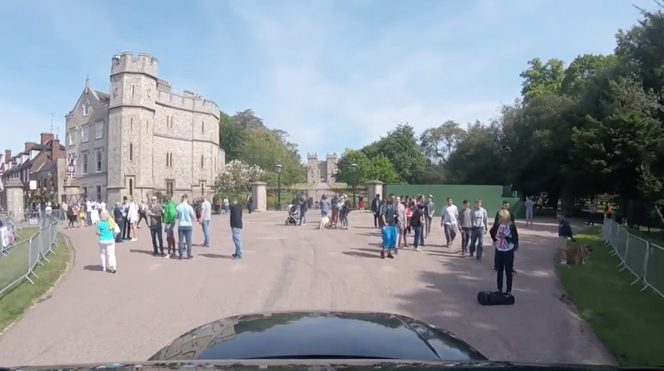 Vor der Einfahrt zu Schloss Windsor stehen Touristengruppen. Am unteren Bildrand ist die schwarze Motorhaube des Autos zu sehen