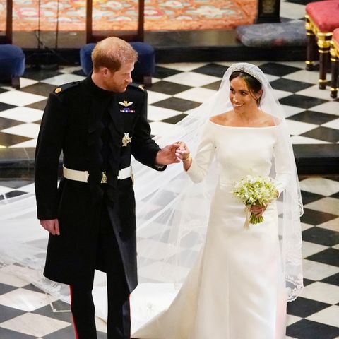 Hand in Hand schreiten Prinz Harry und Meghan Markle als Ehepaar durch die Kirche in Windsor. Sie lächelt ihn an.