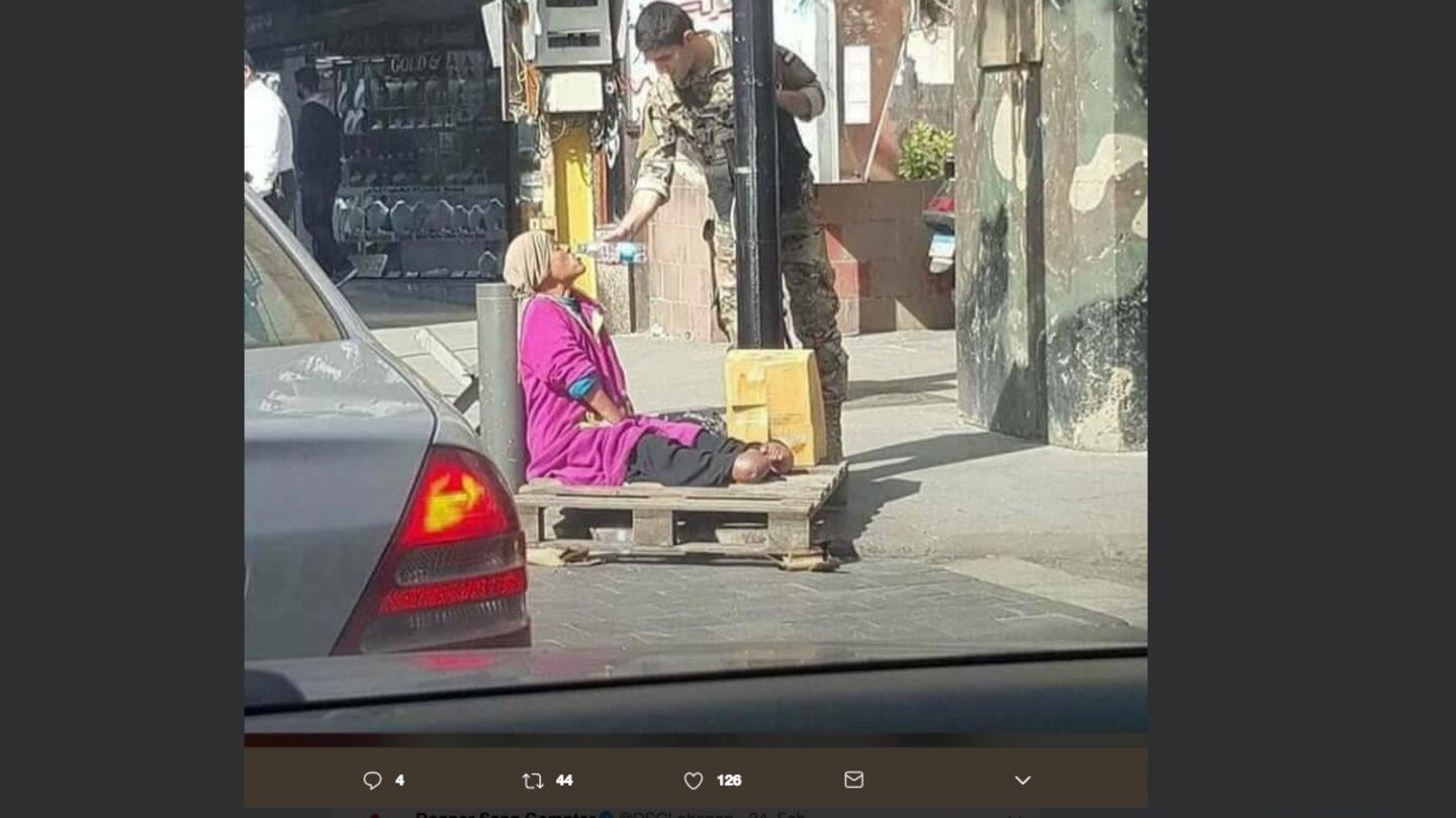 Ein Soldat gibt einer Frau etwas zu Trinken