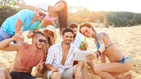 Feiernde Menschen am Strand machen ein Selfie