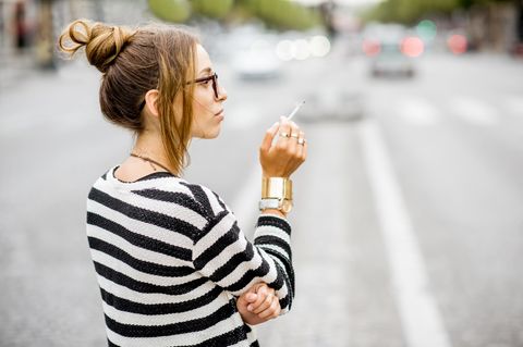 Eine junge Frau raucht auf der Straße eine Zigarette