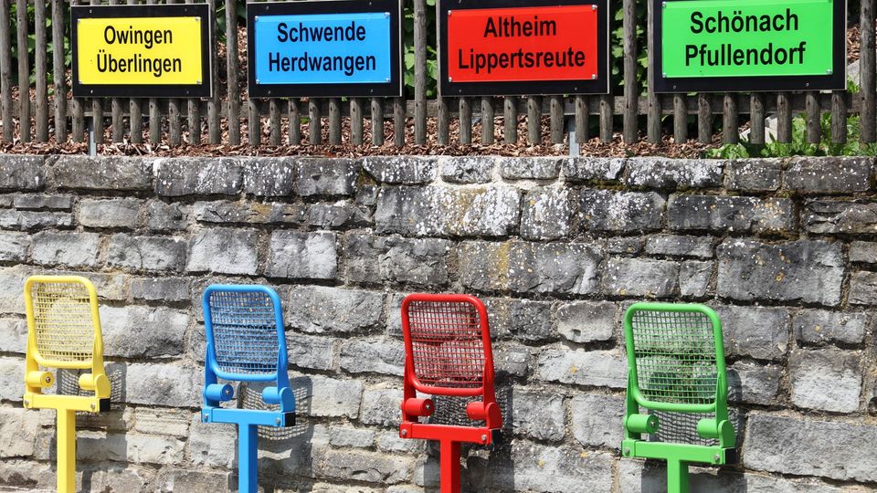 Bitte einsteigen! Weil hier nur ein Bus pro Tag fährt, gibt's in Taisersdorf jetzt die Mitfahrbank bunte Stühle mit Ortsschildern