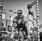 Der Fotograf Dotan Saguy hat drei Jahre lang das Leben am Venice Beach in Los Angeles dokumentiert. In dem vorliegenden Bildband stellt er einige der Menschen vor, die er in dieser Zeit kennengelernt hat. Da ist zum Beispiel der bekannte österreichische Athlet Ike Catcher, der im Hintergrund seinen Astralkörper in die Lüfte stemmt, während vorne ein Gewichtheber schwere Eisen stemmt. Diese Aufnahme stammt vom weltberühmten Muscle Beach: Es ist der Ort, an dem in den 1930er Jahren der Fitness-Boom entstand, der Menschen aus aller Welt anzog und eine einzigartige Mischung aus Bodybuildung und Akrobatik schuf