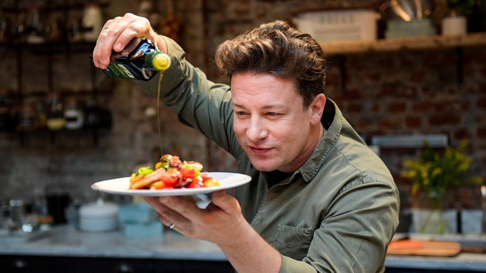 Jamie Oliver gießt Olivenöl über einen Teller mit Essen