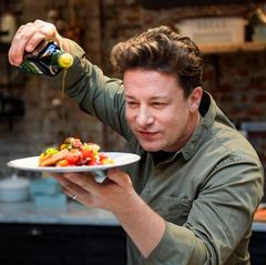 Jamie Oliver gießt Olivenöl über einen Teller mit Essen