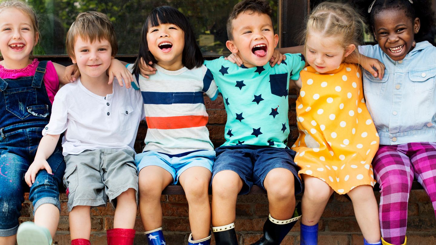 Kinder sitzen nebeneinander und schauen in die Kamera