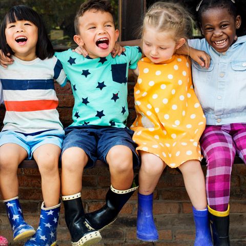 Kinder sitzen nebeneinander und schauen in die Kamera