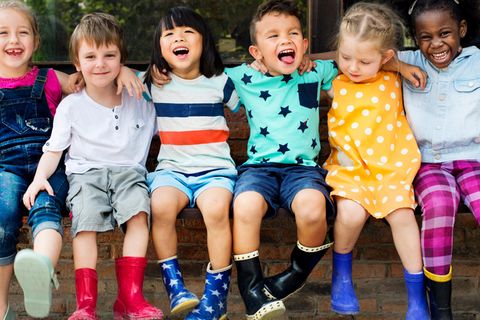 Kinder sitzen nebeneinander und schauen in die Kamera