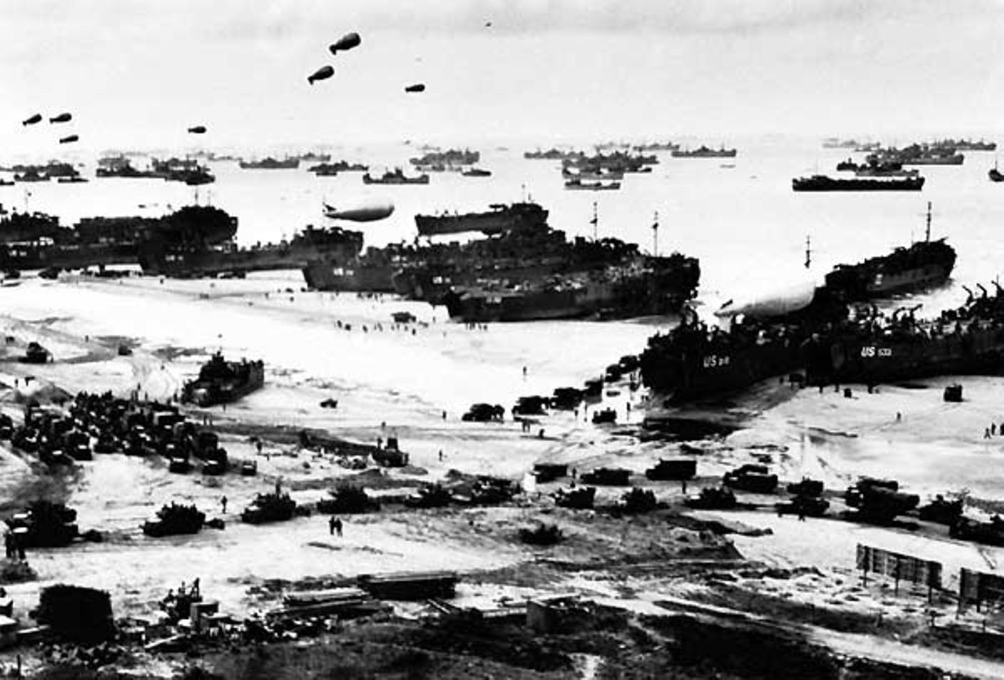 Provisorischer Hafen  Hunderte Schiffe liegen vor der Küste der Normandie. An den breiten Sandstränden entladen landungsboote ihre Fracht. Lastwagen formieren sich zu Marschkolonnen. Über der Szene schweben Fesselballons, die mit ihren Stahltrossen deutschen Fliegern den Weg versperren und so Angriffe verhindern sollen