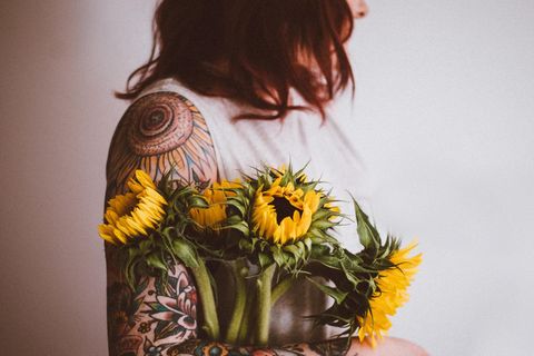 Eine tättowierte Frau hält Blumen im Arm