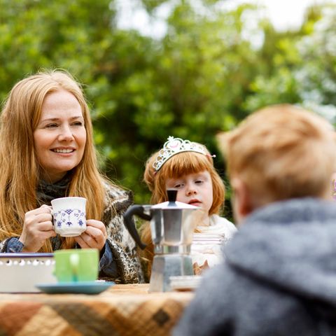 Eine Mutter sitzt mit vier Kindern am Tisch