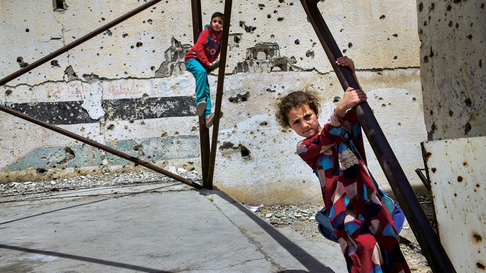 Syrienkrieg: Kinder spielen im Hof der Houari-Boumedienne-Schule, die während der Kämpfe stark beschädigt wurde. Im Haus gegenüber residierte die Religionspolizei des IS Kinder spielen im Hof der Houari-Boumedienne-Schule, die während der Kämpfe stark beschädigt wurde. Im Haus gegenüber residierte die Religionspolizei des IS