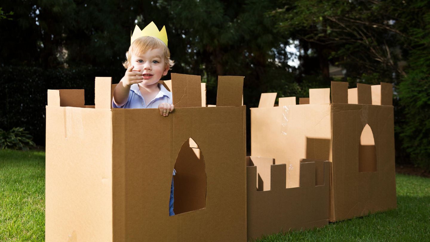 Ein kleiner Junge mit Krone auf dem Kopf in einem Schloss aus Pappe