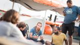 Der deutsch-eritreische Schiffsarzt Robel (rechts sitzend) und der englische Matrose Kim (links daneben) weisen die neue Crew ein 
