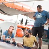 Der deutsch-eritreische Schiffsarzt Robel (rechts sitzend) und der englische Matrose Kim (links daneben) weisen die neue Crew ein 