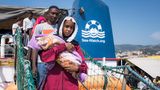 Im sicheren Hafen von Messina, Sizilien: Eine junge Frau aus dem Sudan trägt ihr Baby im Arm. Viele Kinder werden während der Flucht geboren.