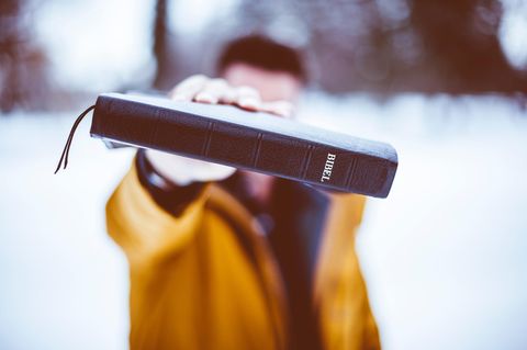 Ein junger Mann hält sich eine Bibel vor das Gesicht