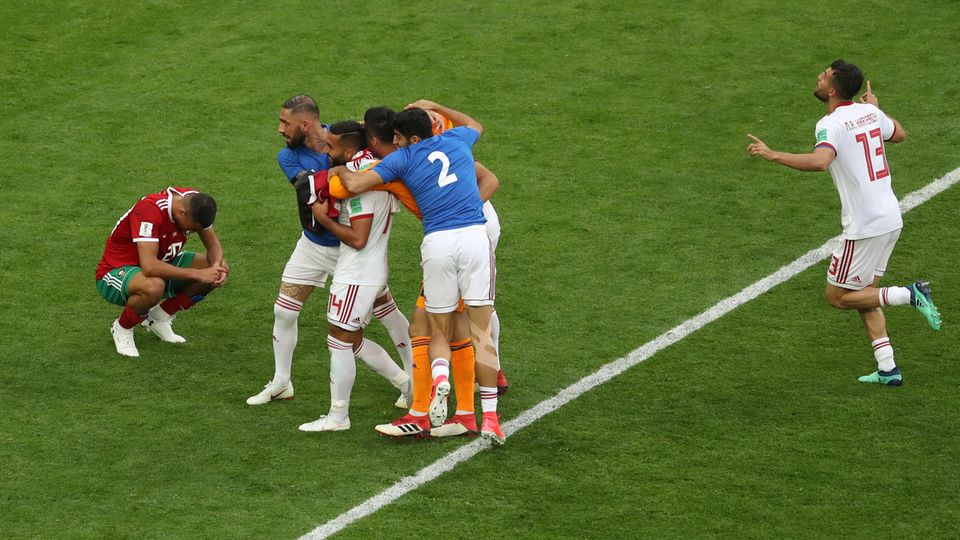 Zwei Welten in einem Bild: Die Iraner in Weiß feiern ihren Last-Minute-Sieg, Unglücksrabe Abouhaddouz ist am Boden zerstört Zwei Welten in einem Bild: Die Iraner in Weiß feiern ihren Last-Minute-Sieg, Unglücksrabe Abouhaddouz ist am Boden zerstört