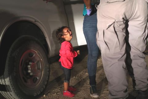 Ein kleines Mädchen aus Honduras sieht weinend zu, seine Mutter von einer texanischen Grenzbeamtin durchsucht wird