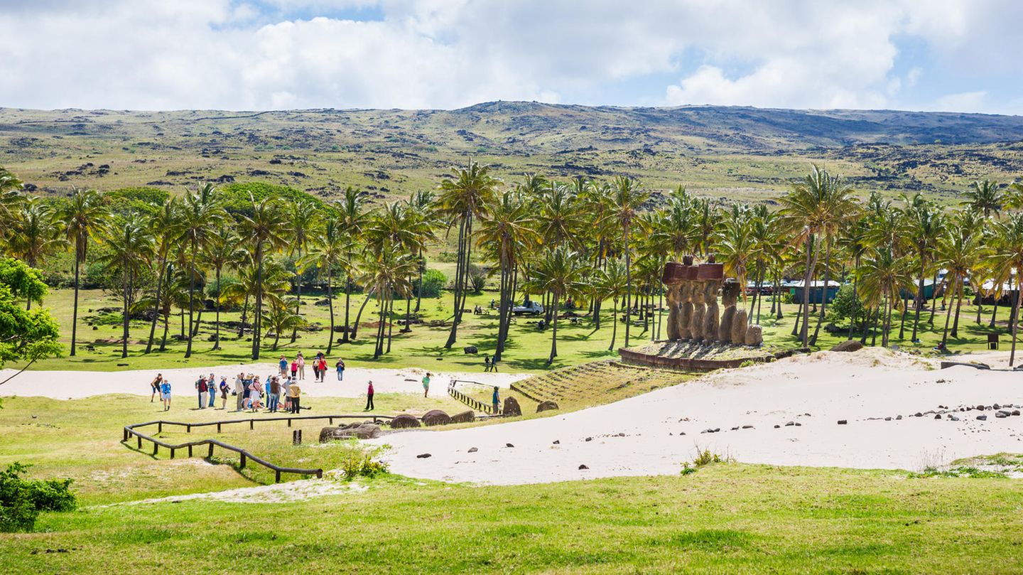 Touristen bewundern eine Gruppe von Moai am Anakena Beach auf der Osterinsel.
