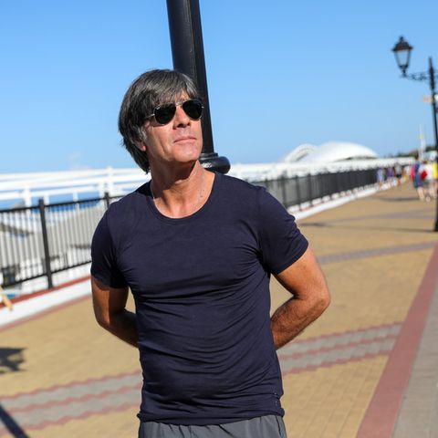 Tiefenentspannt lehnt Bundestrainer Joachim Löw an einer Laterne in Sotschi, den Blick in die Weite schweifen lassend