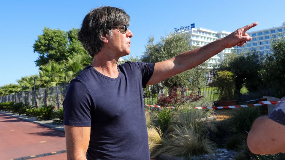 Löw zeigt mit dem Finger in die Ferne, erklärt dem Fotografen offenbar etwas