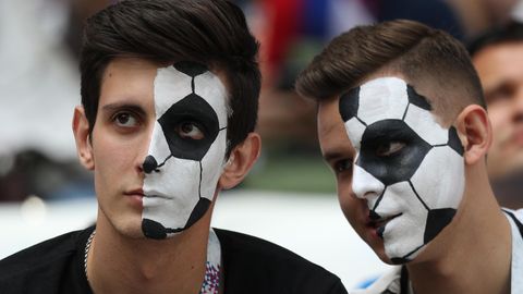 Fußballfans, die sich ein Ballmuster ins Gesicht geschminkt haben