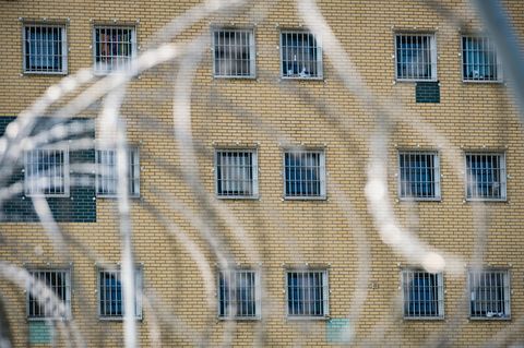 Fenster eine JVA im Hintergrund, Stacheldraht im Vordergrund