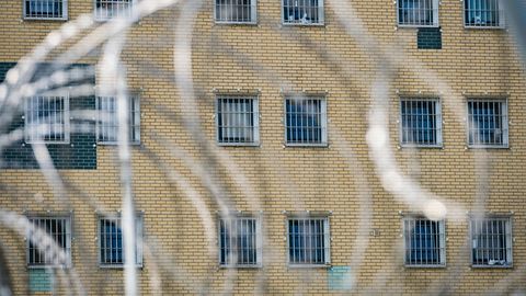 Fenster eine JVA im Hintergrund, Stacheldraht im Vordergrund