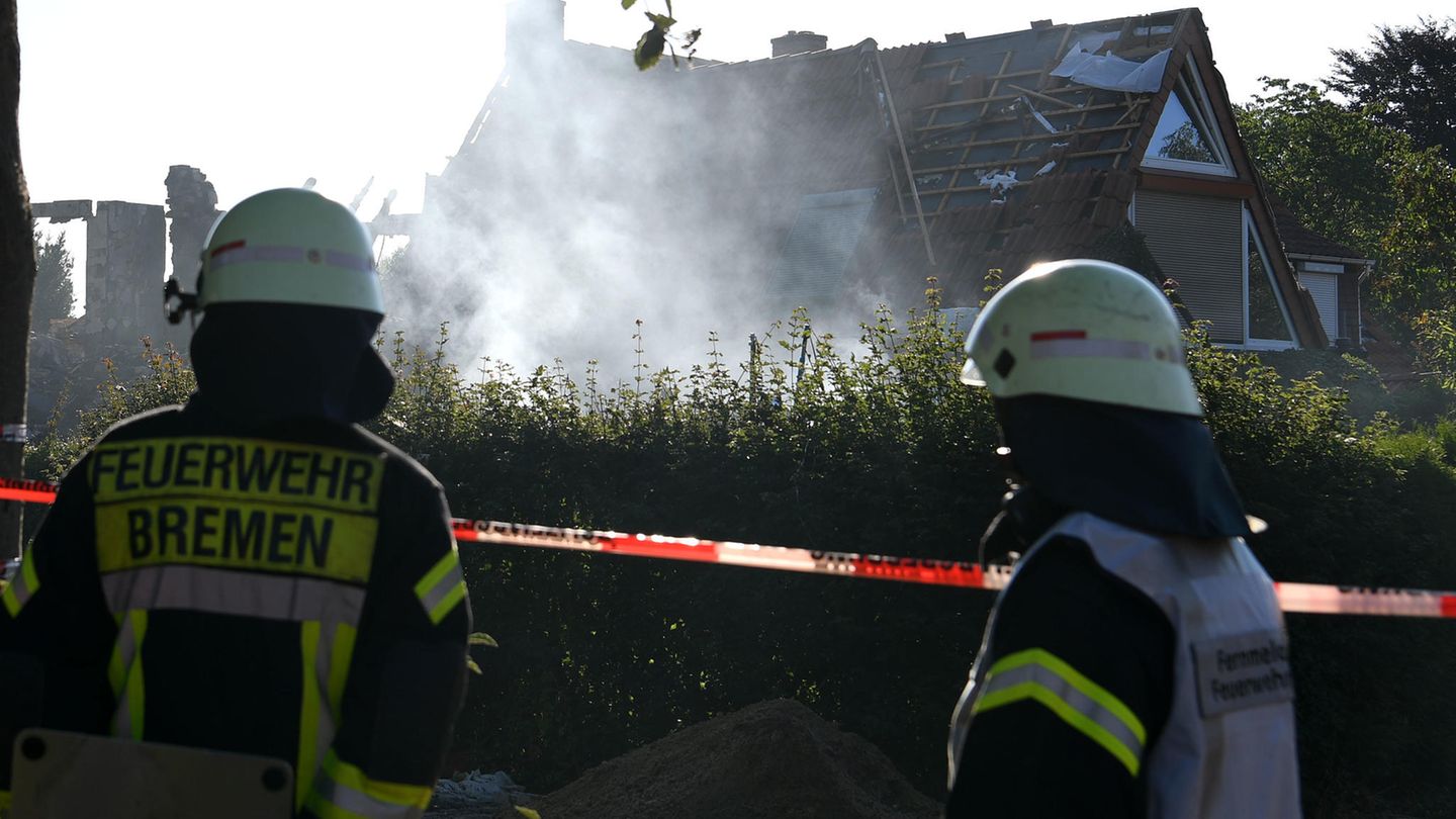 Bremen: Feuerwehrmänner schauen auf das noch rauchende Wohnhaus, das bei einer Explosion zerstört wurde.