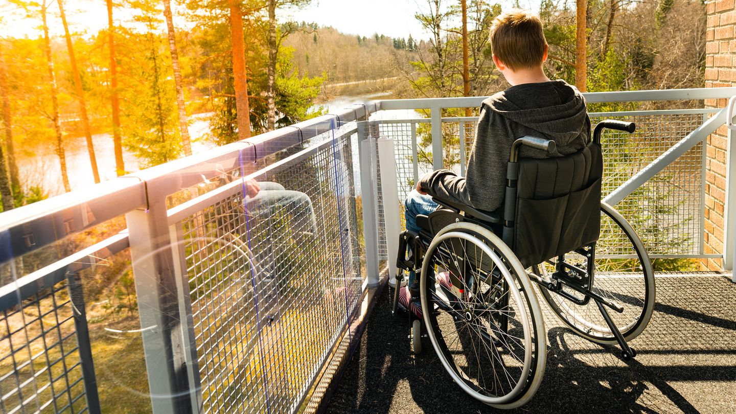 Ein Junge sitzt im Rollstuhl und schaut auf einen See