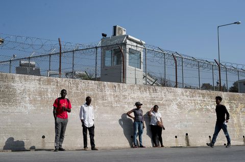 Gruppe von Migranten an der Mauer eines Flüchtlingslagers