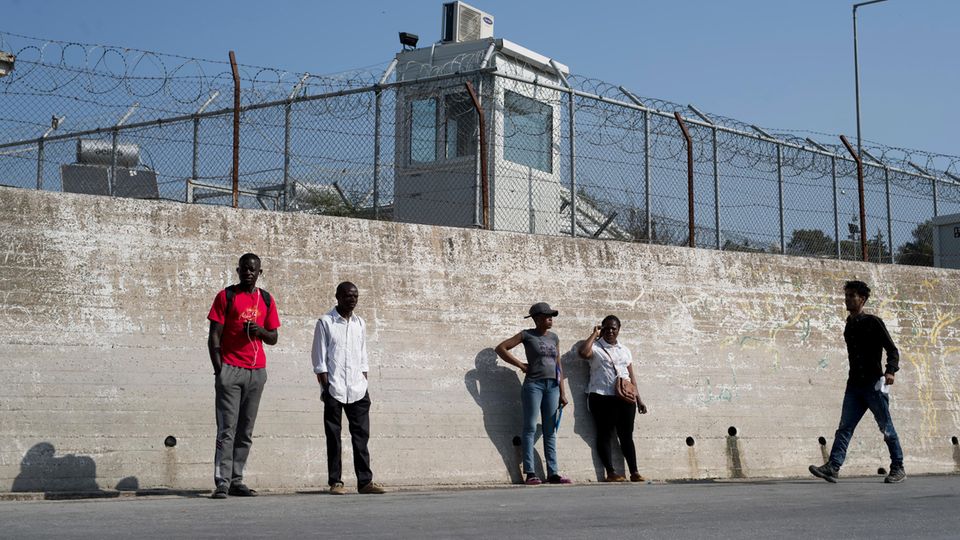 Gruppe von Migranten an der Mauer eines Flüchtlingslagers