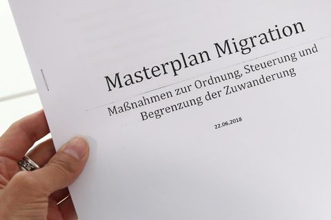 Eine linke Frauenhand hält einen Ausdruck des "Masterplans Migration" der CSU