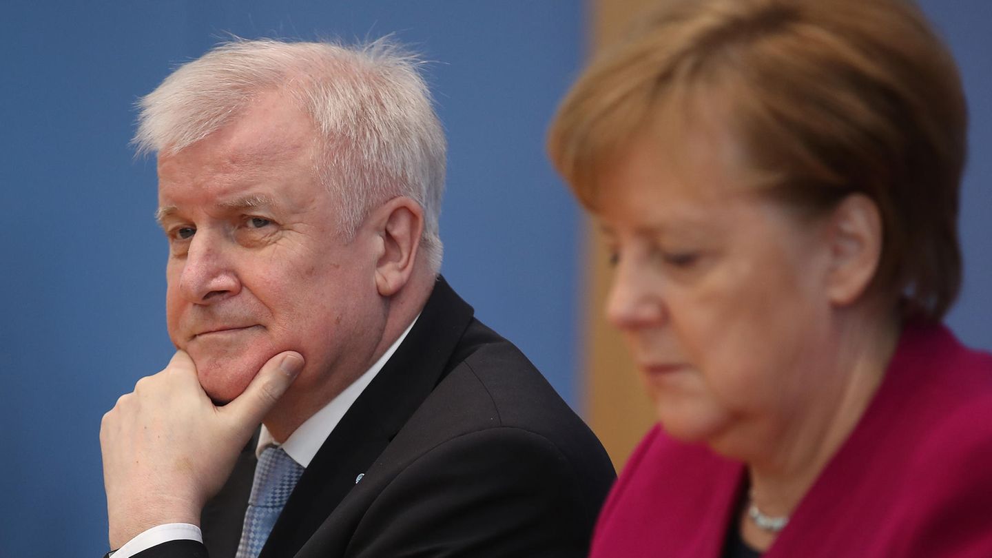 Horst Seehofer schaut skeptisch und stützt sich auf sein Kinn, Angela Merkel schaut auf den Tisch vor sich