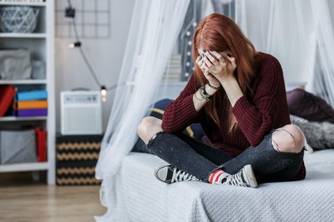 Eine Frau sitzt auf einem Bett und weint