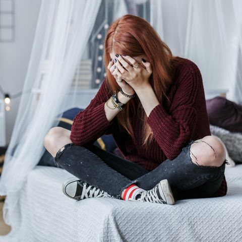 Eine Frau sitzt auf einem Bett und weint