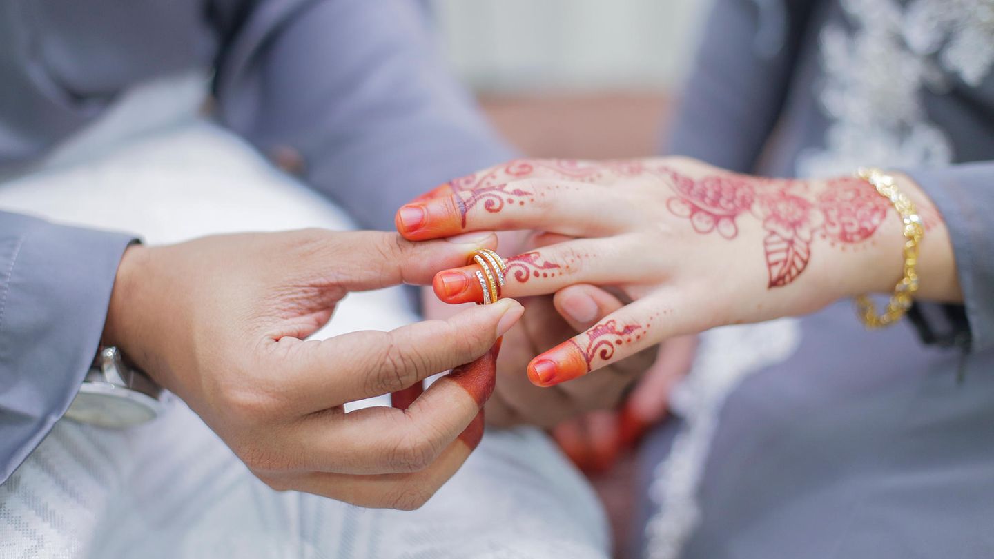 Ein Bräutigam steckt einer Braut einen Ring an den Finger