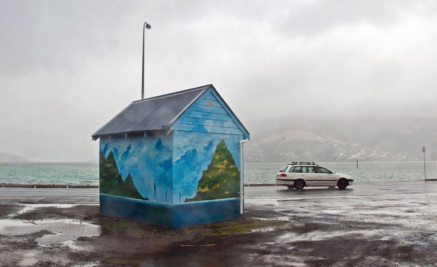 Mit dem Bus zum Albatros   Das mag jetzt hier auf dem Bild nicht so aussehen, aber die Otago Peninsula liegt tatsächlich im Ortsgebiet von Dunedin, der zweitgrößten Stadt auf Neuseelands Südinsel. Und ja, die Menschen, die hier leben, sehnen sich wohl nach besserem Wetter, wie die Blauer-Farbtupfer-Haltestelle beweist. Auf der Halbinsel befindet sich übrigens die einzige Kolonie von Königsalbatrossen der Welt, die auf kontinentalem Festland liegt. Noch ein Grund, hier mal vorbeizuschauen!