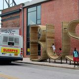 Spaß mit drei Buchstaben  Was schützt vor Regen? Das B. Und wo kann man sich herrlich zurücklehnen? Im S. Vielleicht auch im U, aber nur bei Sonne, denn bei schlechtem Wetter tröpfelt‘s da ja oben rein. Mit der Bushaltestelle an der S. East Street in Highlandtown in Baltimore will das spanische Künstlerkollektiv "mmmm…" dem Warten den Spaß zurückgeben. Die drei Lettern sind übrigens mehr als vier Meter hoch. Was auch Kurzsichtigen beim Auffinden durchaus Freude bereitet.