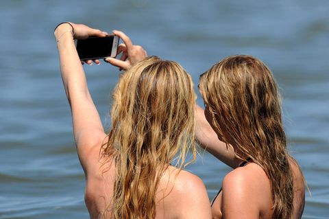 Zwei jungen Frauen machen in der Nordsee im Wasser ein Selfie.
