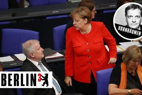 Im Bundestag steht Angela Merkel im roten Blazer vor Horst Seehofer, der auf seinem blauen Stuhl sitzt