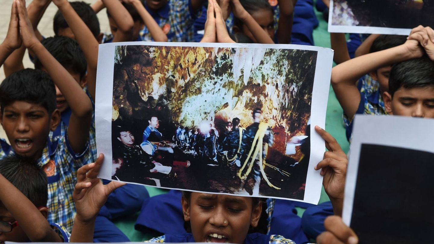 Indische Schulkinder halten Fotos der eingeschlossenen Jungs in Thailand hoch