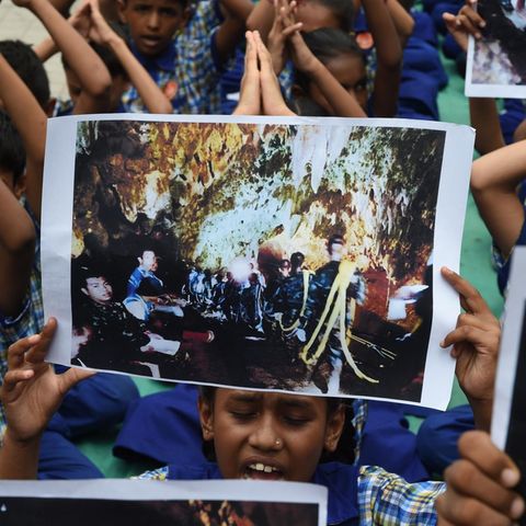 Indische Schulkinder halten Fotos der eingeschlossenen Jungs in Thailand hoch