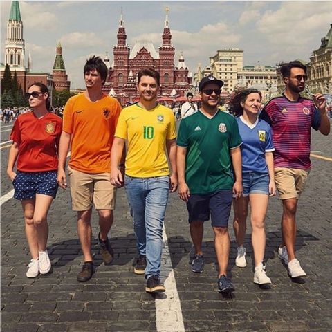 Sechs Brasilianer und Brasilianerinnen gehen in bunten Fußballtrikots über die Straße